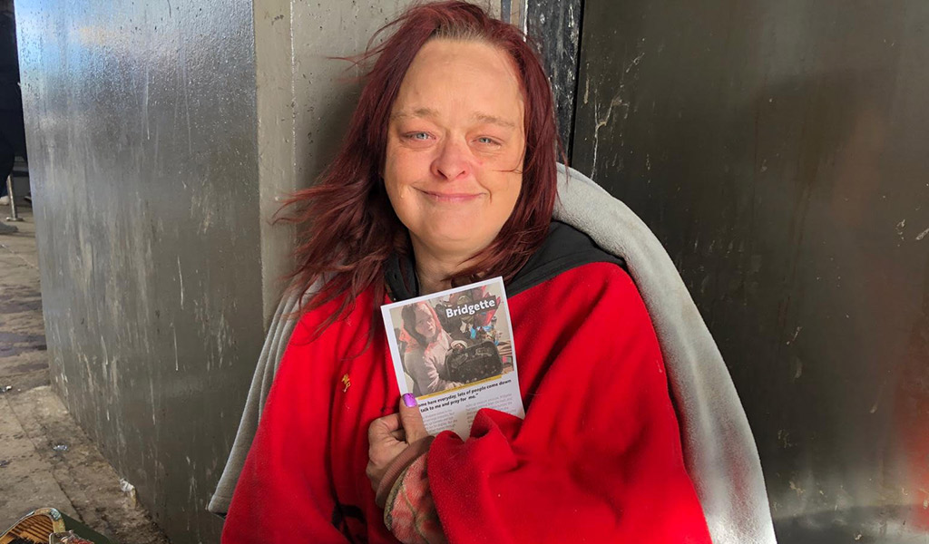 homeless lady holding leaflet